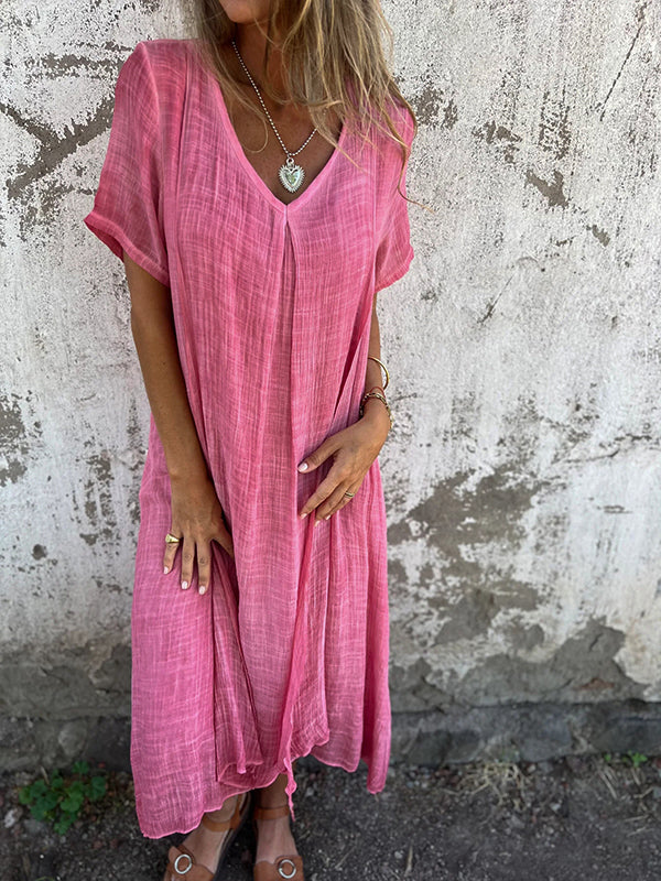 Woman wearing the Andrea™ flowing V-neck dress with short sleeves, standing relaxed in warm sunlight.