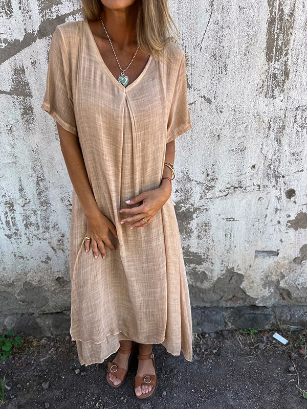 Woman wearing the Andrea™ flowing V-neck dress with short sleeves, standing relaxed in warm sunlight.