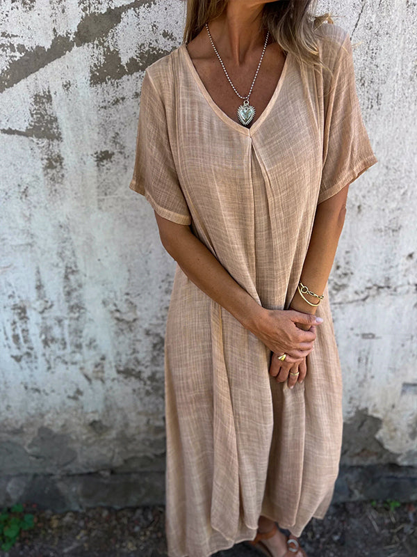 Woman wearing the Andrea™ flowing V-neck dress with short sleeves, standing relaxed in warm sunlight.