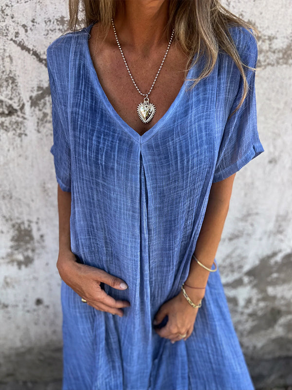 Woman wearing the Andrea™ flowing V-neck dress with short sleeves, standing relaxed in warm sunlight.