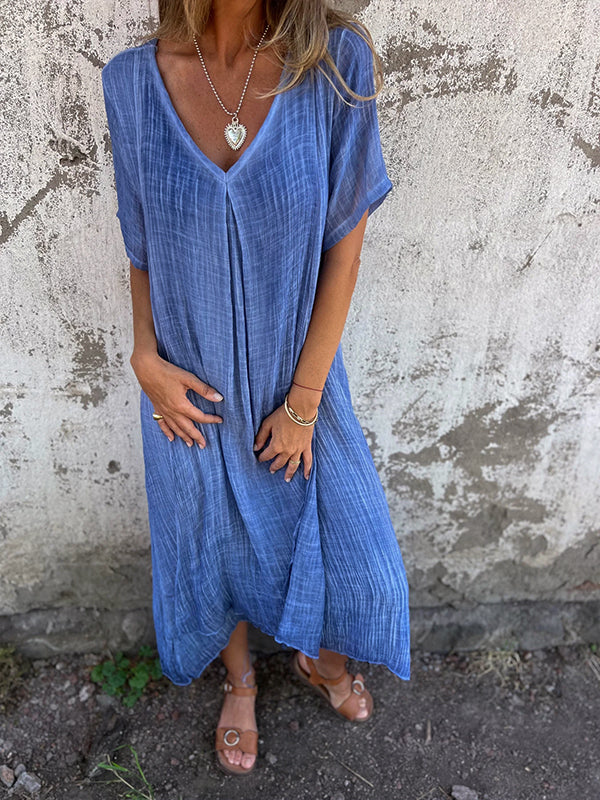 Woman wearing the Andrea™ flowing V-neck dress with short sleeves, standing relaxed in warm sunlight.