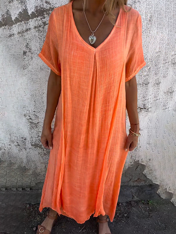 Woman wearing the Andrea™ flowing V-neck dress with short sleeves, standing relaxed in warm sunlight.