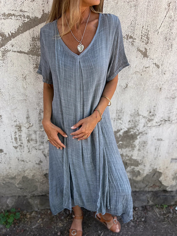 Woman wearing the Andrea™ flowing V-neck dress with short sleeves, standing relaxed in warm sunlight.