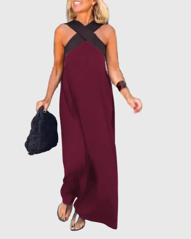 Woman wearing the Julie halterneck maxi dress in navy with a contrast crossover neckline, walking outdoors.