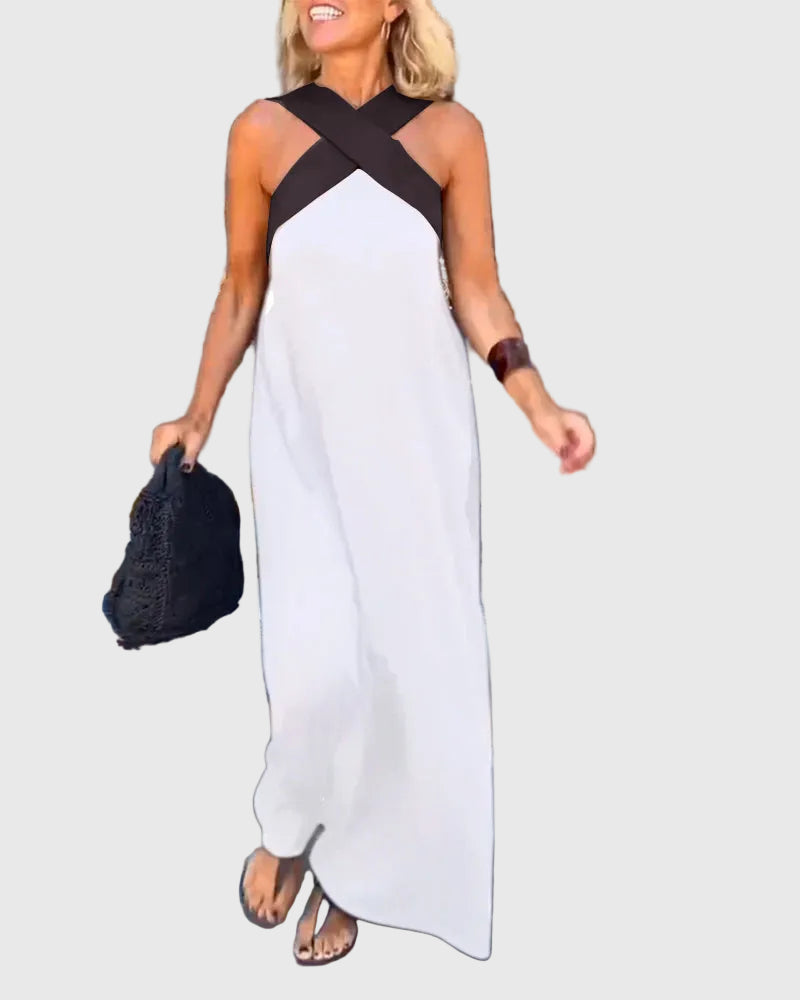 Woman wearing the Julie halterneck maxi dress in navy with a contrast crossover neckline, walking outdoors.