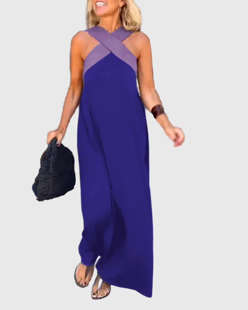 Woman wearing the Julie halterneck maxi dress in navy with a contrast crossover neckline, walking outdoors.