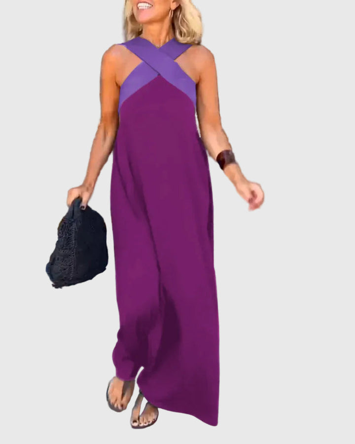 Woman wearing the Julie halterneck maxi dress in navy with a contrast crossover neckline, walking outdoors.