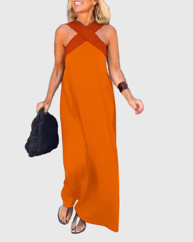Woman wearing the Julie halterneck maxi dress in navy with a contrast crossover neckline, walking outdoors.