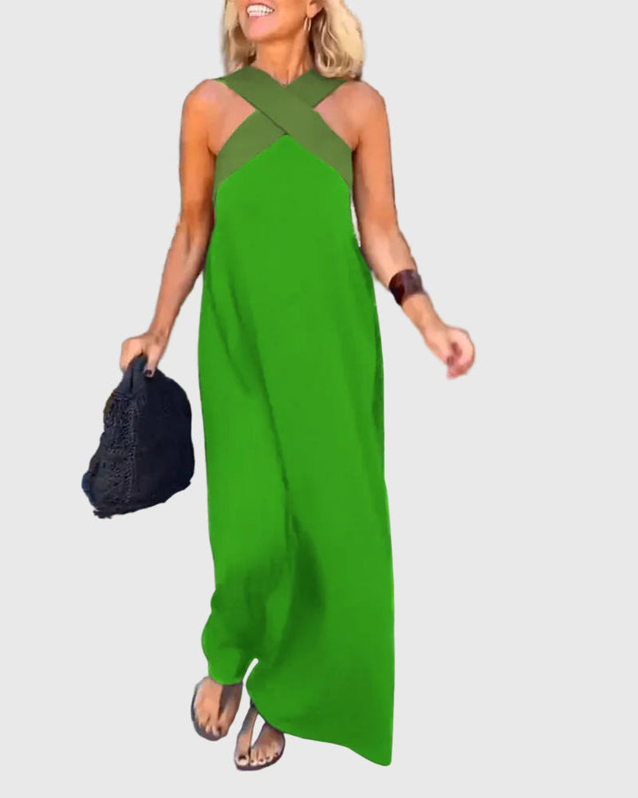 Woman wearing the Julie halterneck maxi dress in navy with a contrast crossover neckline, walking outdoors.