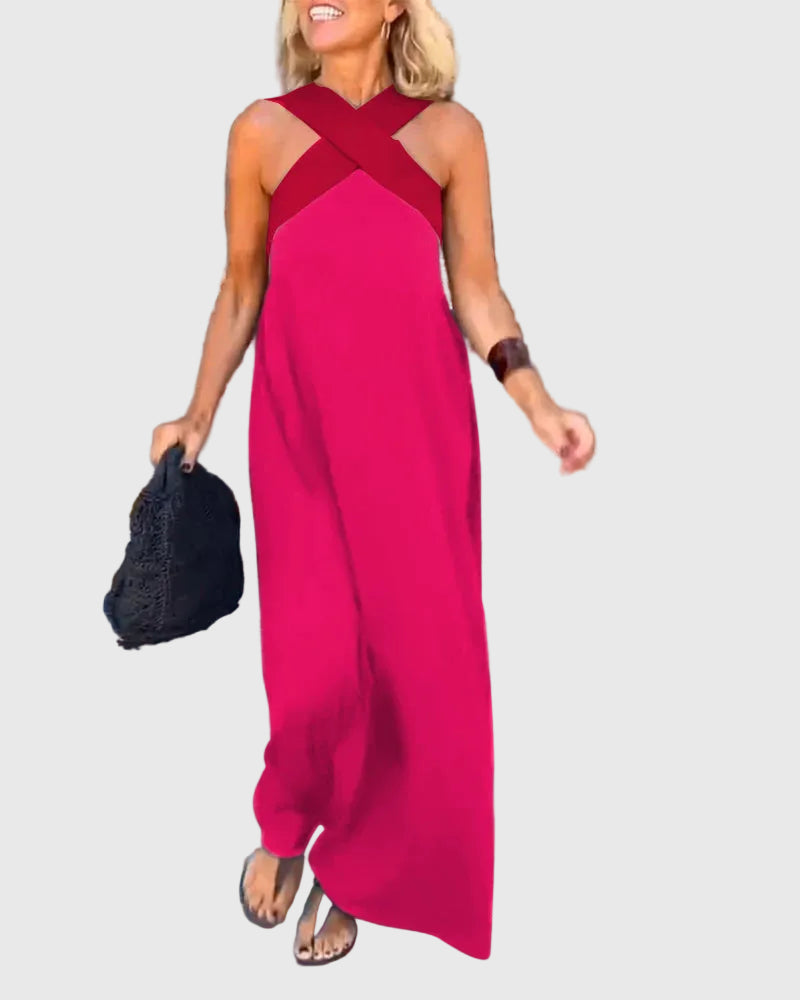 Woman wearing the Julie halterneck maxi dress in navy with a contrast crossover neckline, walking outdoors.