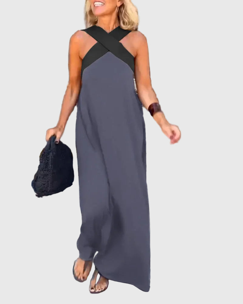 Woman wearing the Julie halterneck maxi dress in navy with a contrast crossover neckline, walking outdoors.