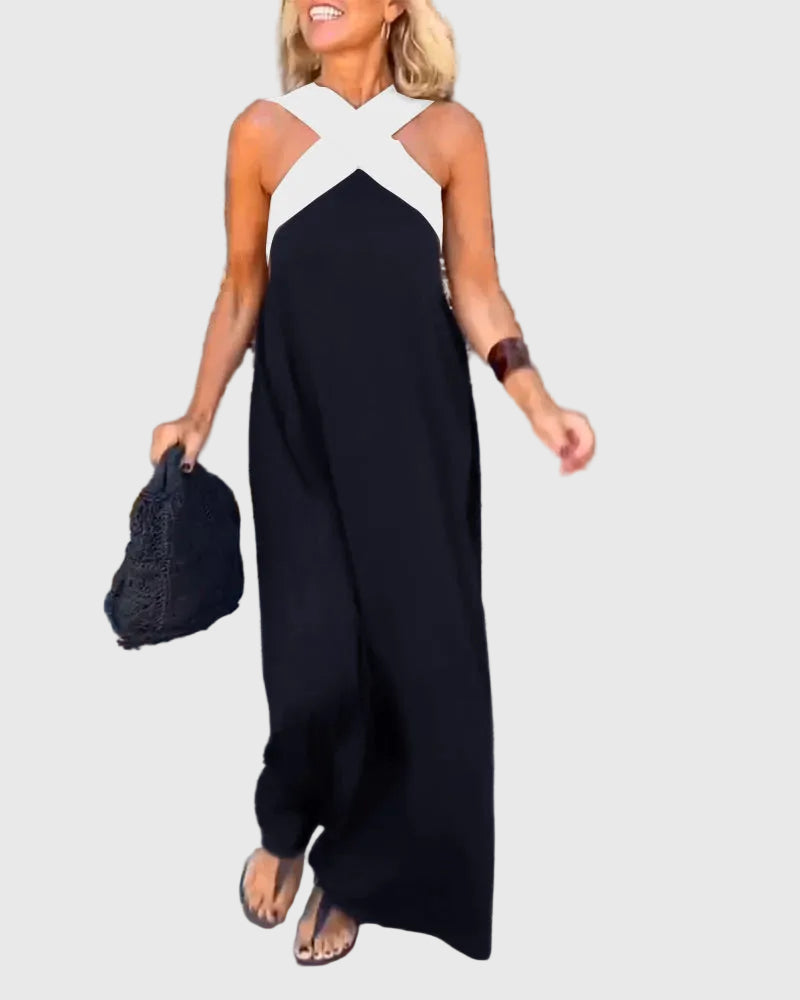 Woman wearing the Julie halterneck maxi dress in navy with a contrast crossover neckline, walking outdoors.