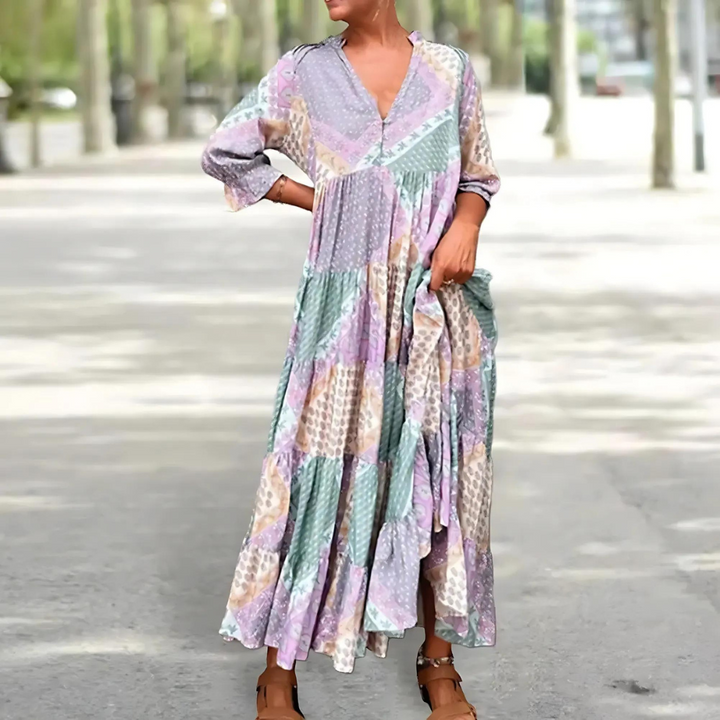 Woman in the Manon patchwork print maxi dress with a V-neckline, standing relaxed in soft summer light.