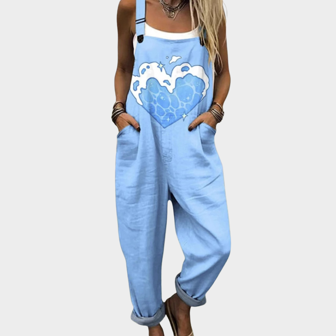 Woman wearing light blue overalls with a large heart and cloud print, adjustable straps, cheerful and relaxed.