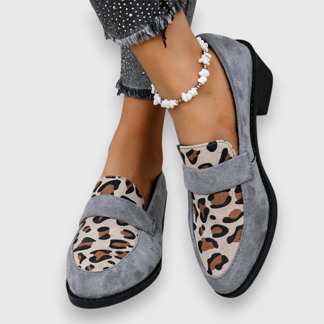 A woman wearing tan leopard print loafers with a low block heel, styled with jeans.