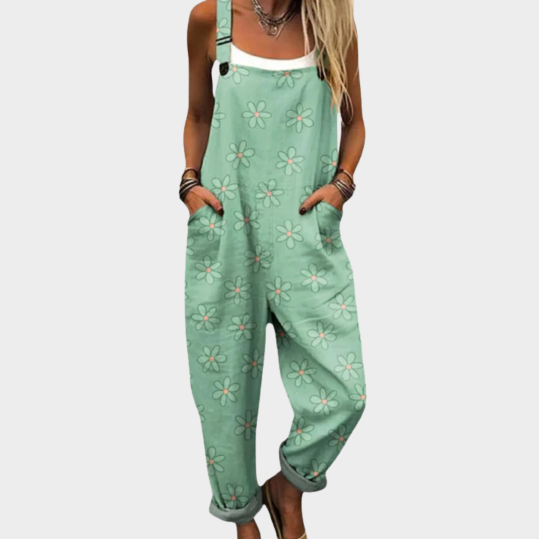 Woman wearing sage green overalls with delicate white blooms, adjustable straps, feminine and relaxed.