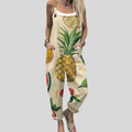 A woman wearing cream overalls printed with pineapples, watermelon and lemons, with adjustable straps.