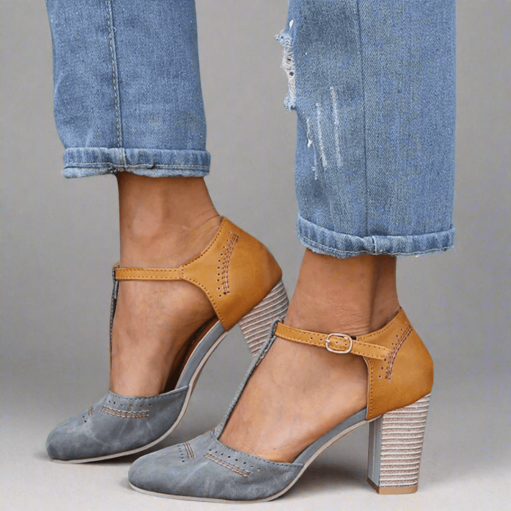 A woman wearing two-tone T-strap heels in navy and mustard tan with a stacked block heel, styled with cropped jeans.