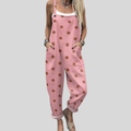 A woman wearing soft pink overalls with terracotta polka dots and adjustable straps.