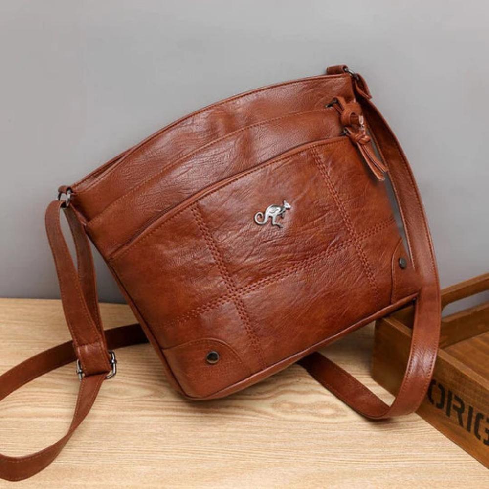 A woman wearing a brown cross-body bag across her body while out in the city