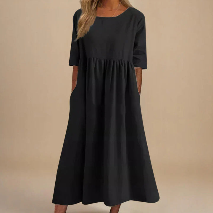 A woman wearing the Shannon flowing day dress with a gathered waist and elbow-length sleeves.