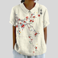 A woman wearing a flowing floral top with a neat polo collar, styled for an easy everyday look.