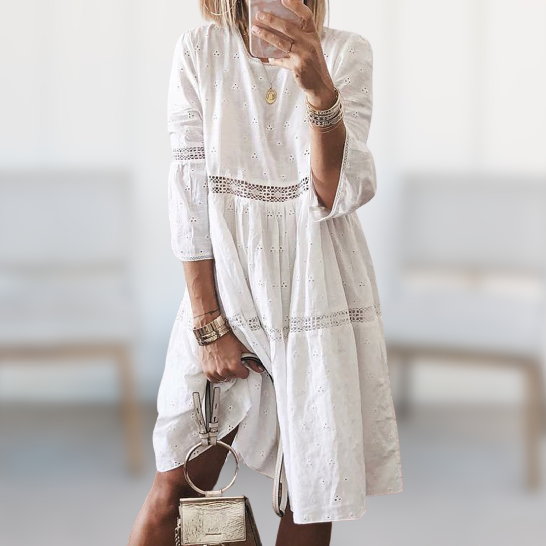 Woman wearing the Megan™ elegant summer dress with a round neckline and flowing silhouette, standing outdoors on a sunny day.
