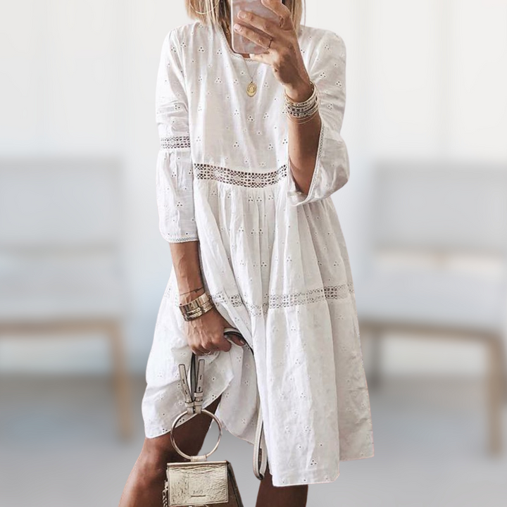 Woman wearing the Megan™ elegant summer dress with a round neckline and flowing silhouette, standing outdoors on a sunny day.