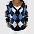 A woman wearing a navy and blue argyle button cardigan over a white top.