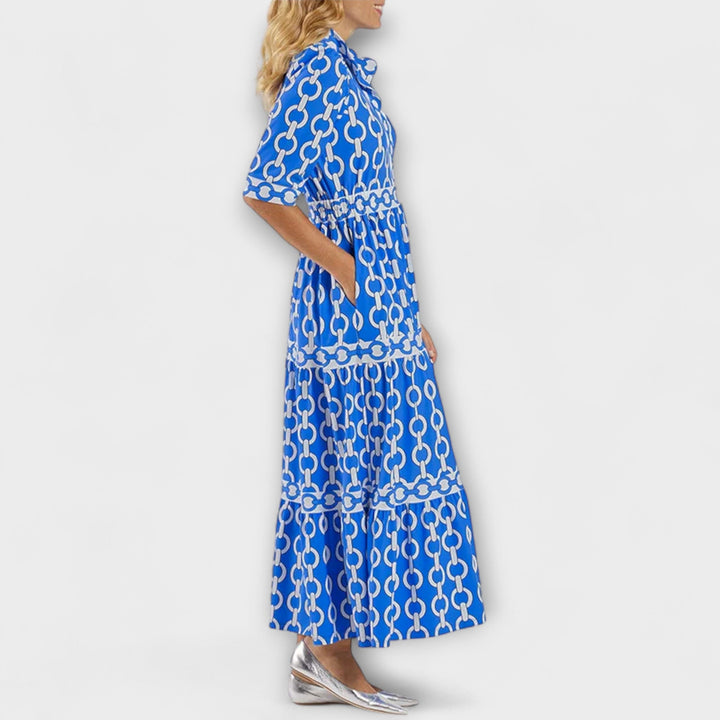A woman wearing a flowing chain print midi dress that drapes elegantly as she walks.
