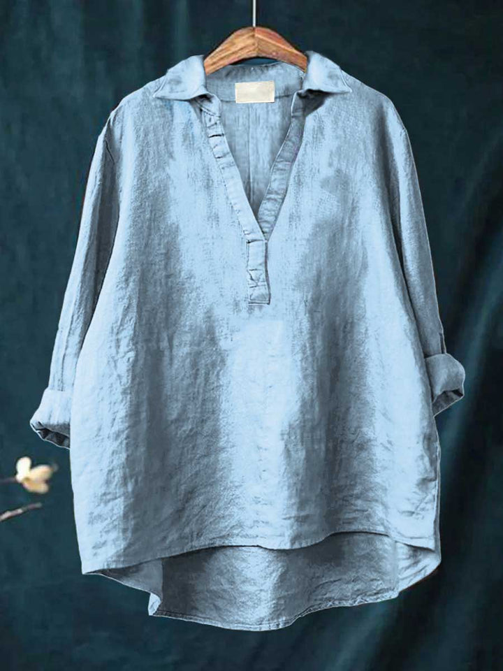 A woman wearing an elegant solid-colour summer blouse with an open V-neck, looking fresh and stylish on a warm day.