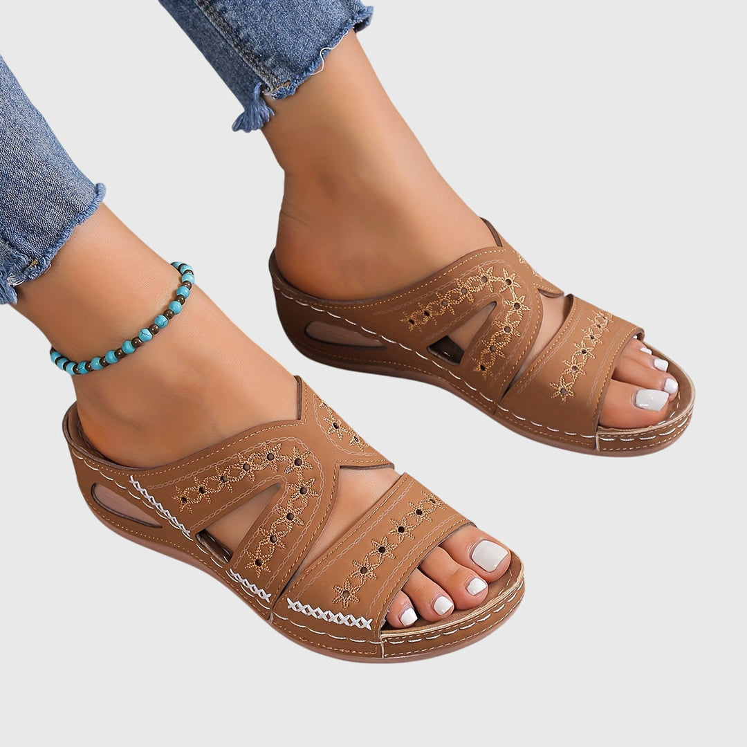 A woman walking gracefully in elegant wide-fit support sandals with an open-front design.