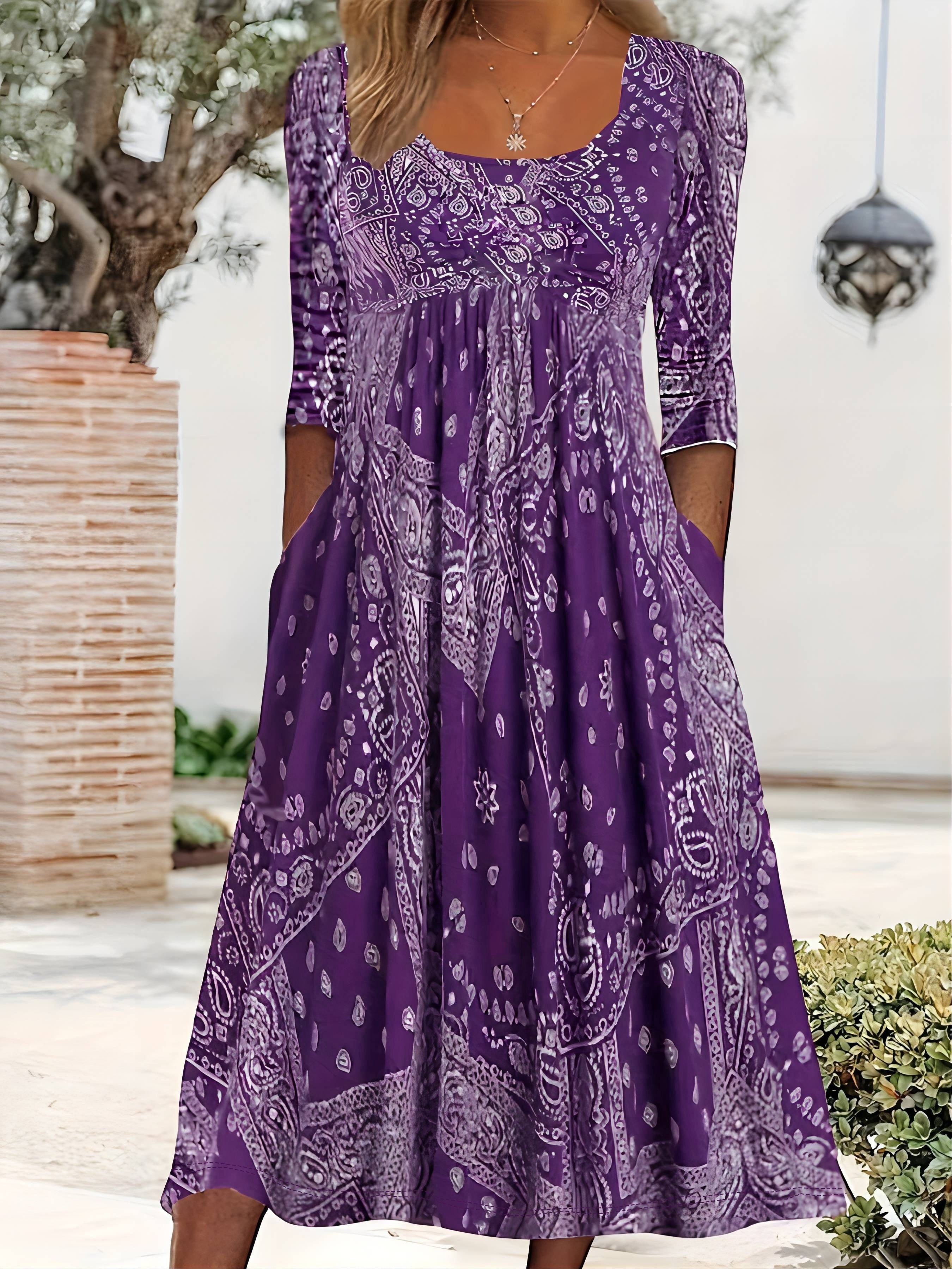 A woman wearing the Maria long sleeve grey paisley midi dress with a square neckline and flowing skirt, styled for a relaxed day out.