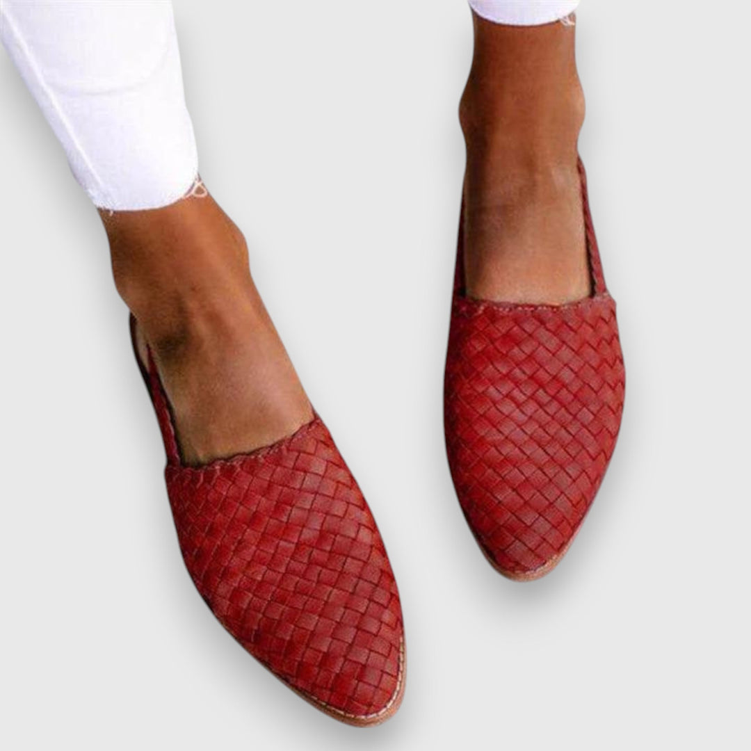 A woman wearing warm brown woven pointed-toe slingback flats with white cropped pants.