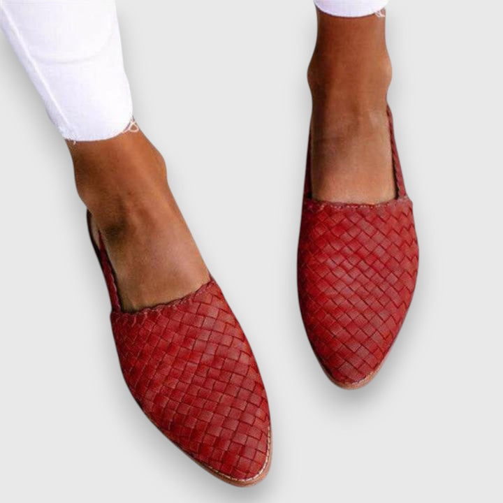 A woman wearing warm brown woven pointed-toe slingback flats with white cropped pants.
