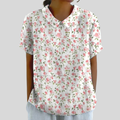 A woman wearing an elegant floral top with a polo collar, looking feminine and comfortable.