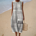 A woman wearing a breezy sleeveless summer dress with an elegant pattern, smiling in the sunshine.