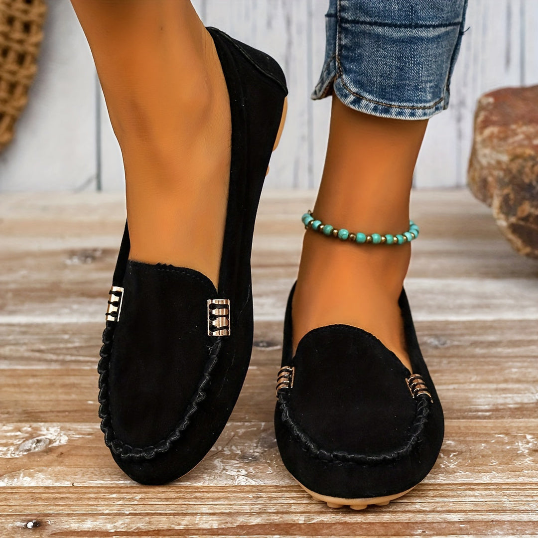 A woman in a ballet-flat loafer stepping lightly along a bright pavement.