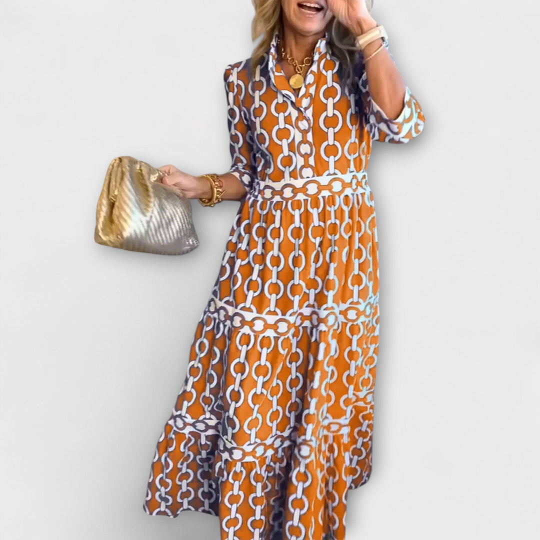 A woman wearing a flowing chain print midi dress that drapes elegantly as she walks.