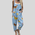 A woman wearing light blue overalls printed with cheerful hens and little chicks, with adjustable straps.