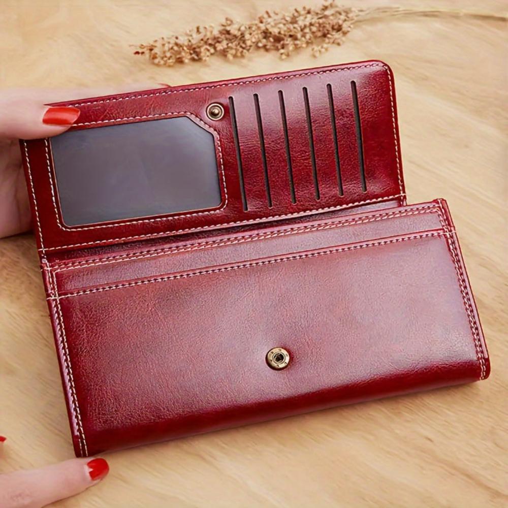 A woman holding a long flap-over wallet, tucking a card into its slot.