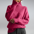 A woman in a stand-collar sweater with an elegant drape, styled with tailored pants.