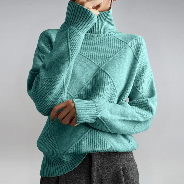 A woman in a stand-collar sweater with an elegant drape, styled with tailored pants.