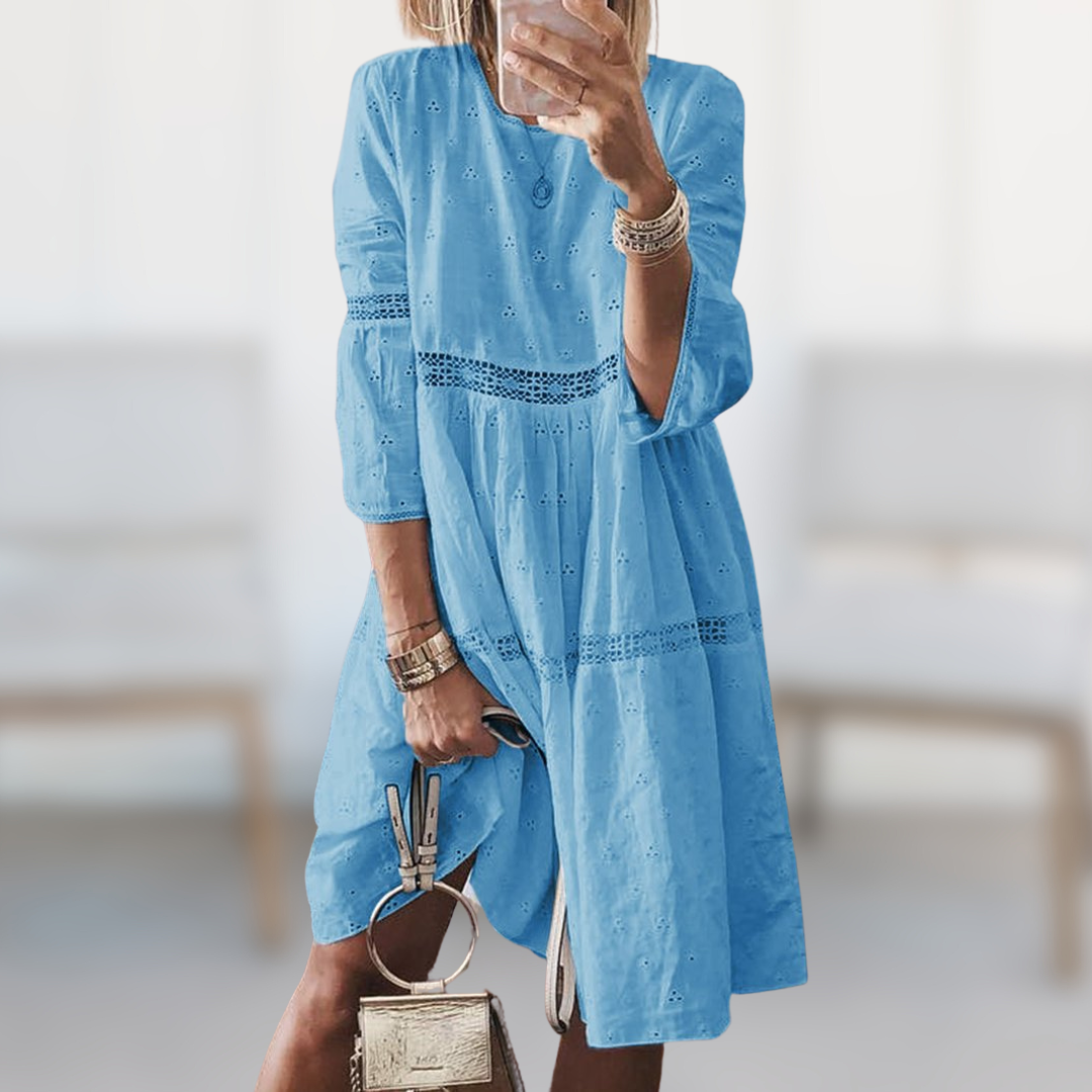 Woman wearing the Megan™ elegant summer dress with a round neckline and flowing silhouette, standing outdoors on a sunny day.