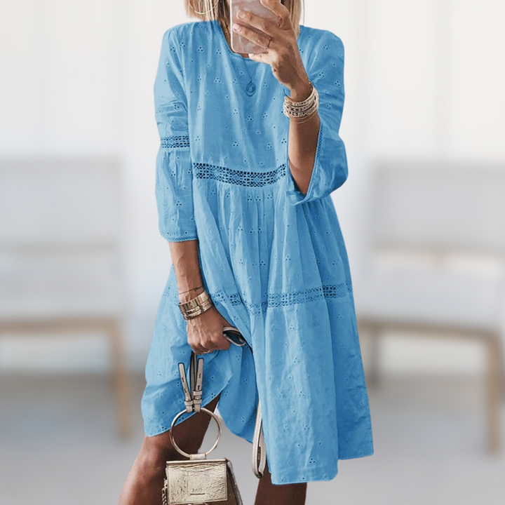 Woman wearing the Megan™ elegant summer dress with a round neckline and flowing silhouette, standing outdoors on a sunny day.
