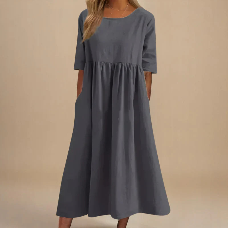 A woman wearing the Shannon flowing day dress with a gathered waist and elbow-length sleeves.