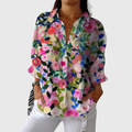 A woman wearing a loose colourful printed blouse with adjustable sleeves, styled with jeans for a bright, comfortable day out.