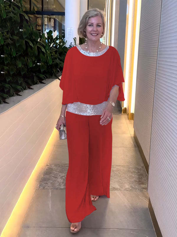 A woman wearing an embellished blouse-style top with softly flowing wide evening pants.
