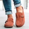 A woman wearing soft taupe buckle clog mules with cropped jeans on a city stroll.