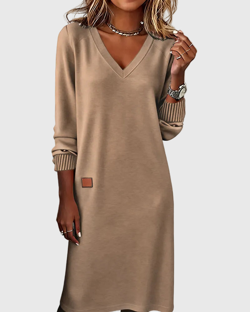 Woman wearing the Susan flowing elegant dress in beige, standing relaxed and smiling.